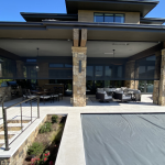 Luxury outdoor patio with retractable screens providing shade and privacy, overlooking a covered pool area.